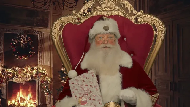 Santa in his red suit on a gold throne, holding a wrapped gift